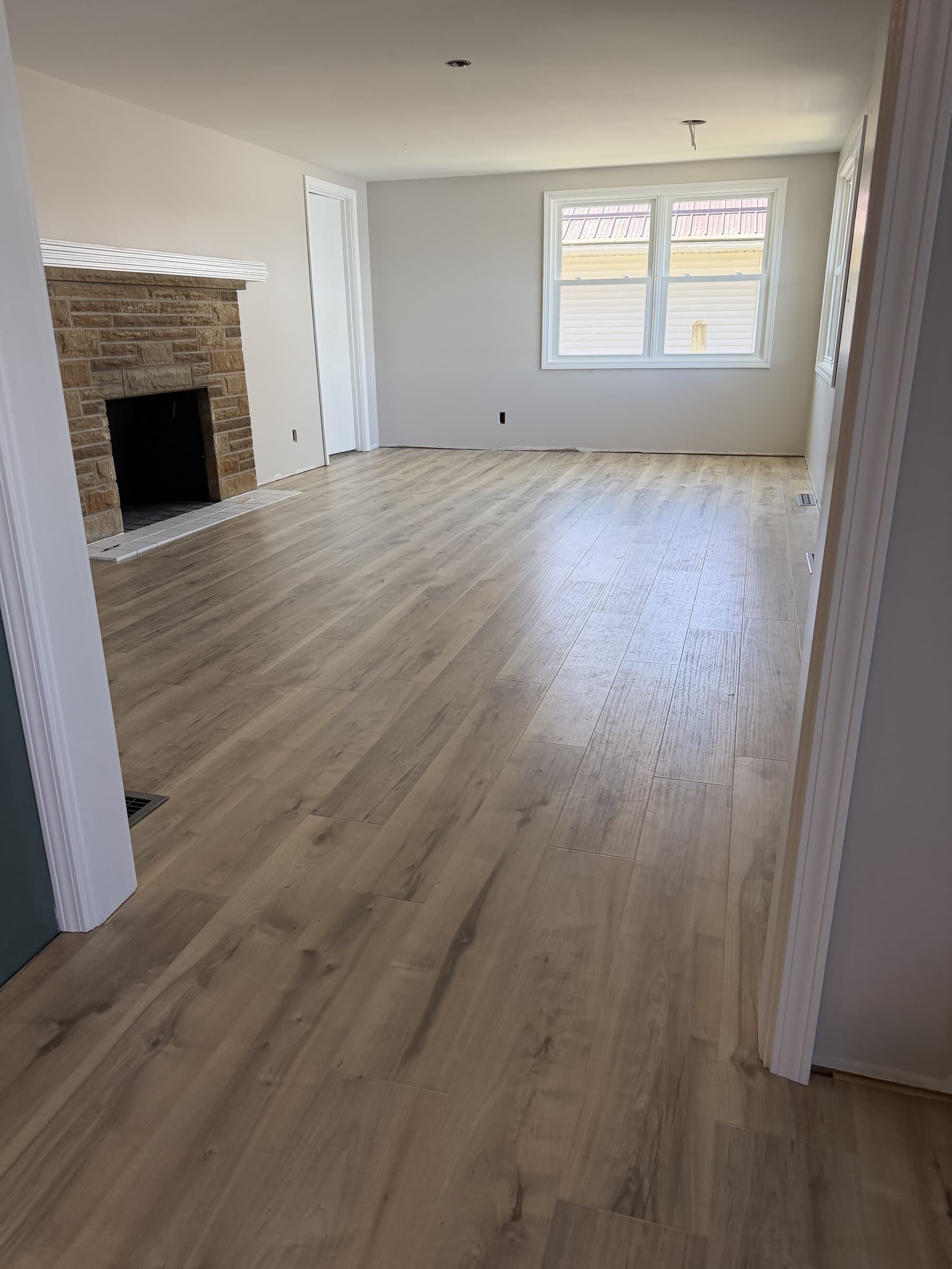 Renovated living room with stone fireplace and wide-plank floor